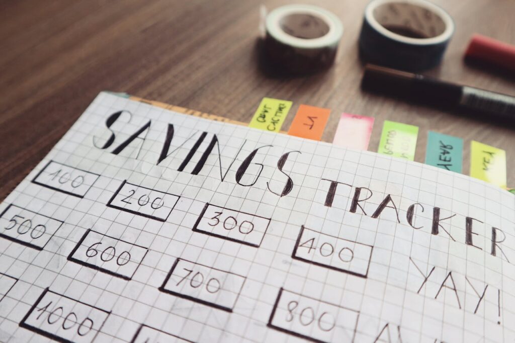 Close-up of a handmade savings tracker with colored tabs on a wooden table, ideal for financial planning visuals.